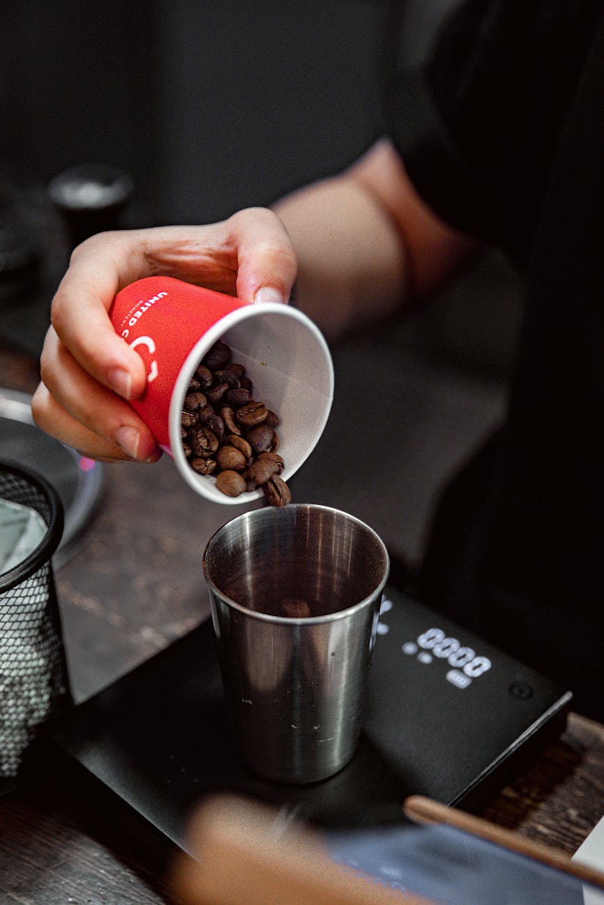 pouring coffee beans into a metal cup at cafe